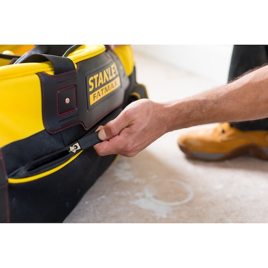 STANLEY FMST82706-1 tool bag in yellow and black, side pocket open by hand, close-up photo.