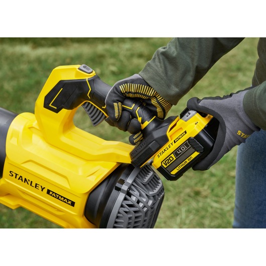 STANLEY SFMCBL730M1 cordless blower close-up with gloved hand installing battery, outdoors.