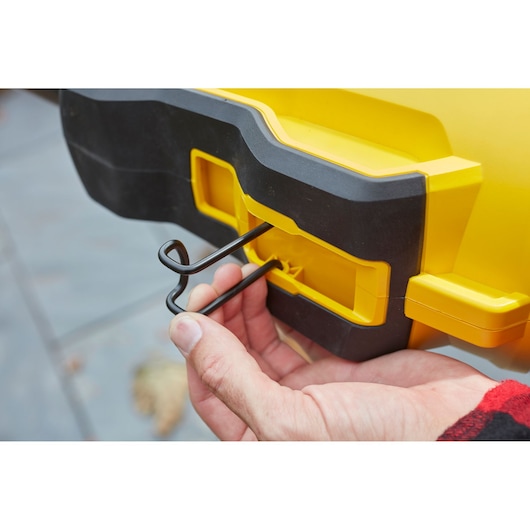 Photo of STANLEY SFMCBL7B blower showing close-up of hand attaching wire stand to yellow and black housing.