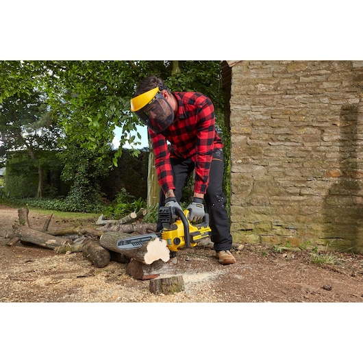Photo of STANLEY SFMCCS630B chainsaw in outdoor use cutting logs, operator wearing safety gear.
