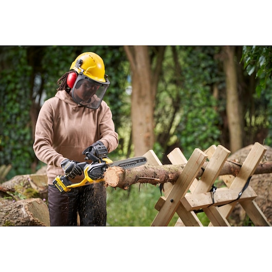 STANLEY SFMCCS730M1 cordless chainsaw in use cutting a log outdoors, person wearing safety gear.
