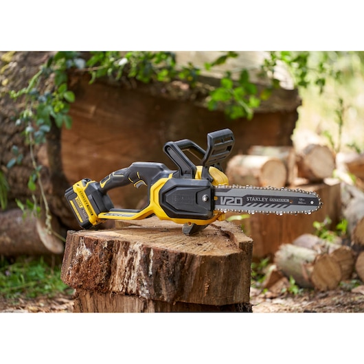 STANLEY SFMCCS730M1 cordless chainsaw in black and yellow resting on a cut log outdoors.