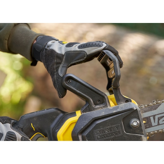 STANLEY SFMCCS730M1 chainsaw close-up, glove hand on handle outdoors.