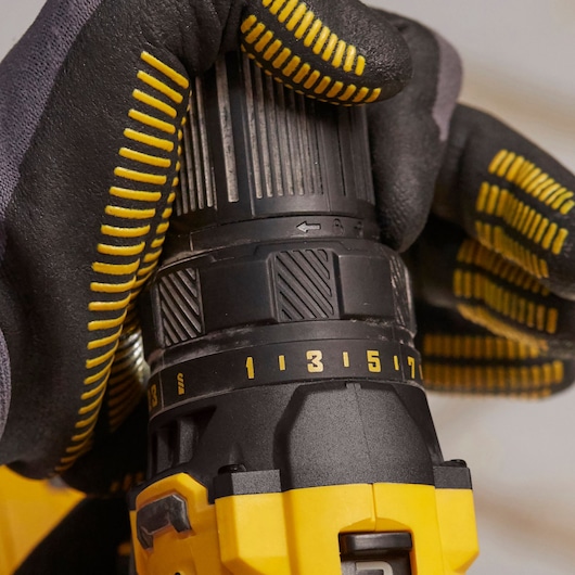 STANLEY SFMCD700C2K drill in use, close-up side angle, black and yellow glove adjusting torque settings.