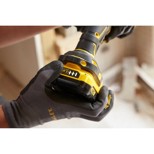 STANLEY SFMCD700C2S cordless drill held in gloved hands, close-up of battery and grip, construction setting.