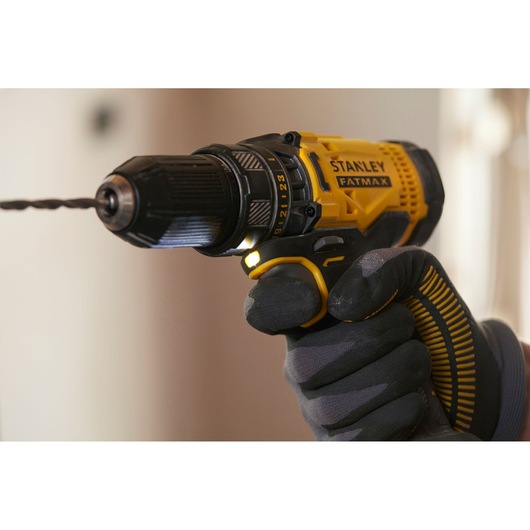 STANLEY SFMCD700C2S cordless drill with yellow and black grip, close-up in gloved hand, side view.
