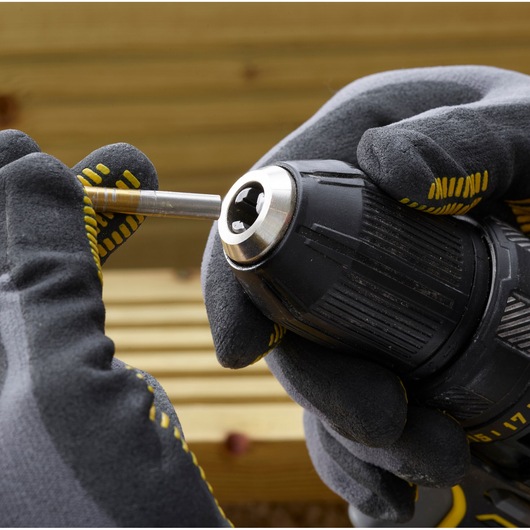 STANLEY SFMCD700C2S drill close-up with gloved hands inserting a drill bit, photography product category.