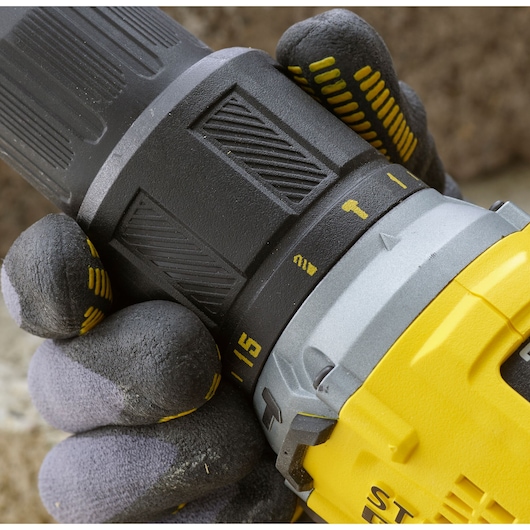 Close-up of STANLEY SFMCD715D1A cordless drill, side view showing grip and adjustment settings, held with gloved hand.