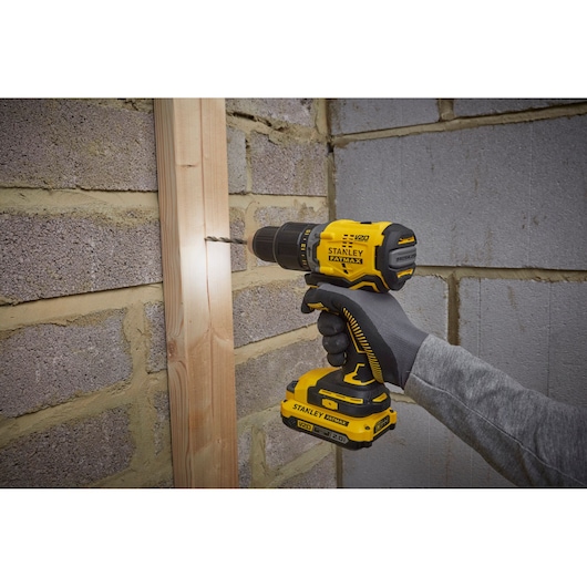 Photo of STANLEY SFMCD715D2F cordless drill in use on wood and brick wall.