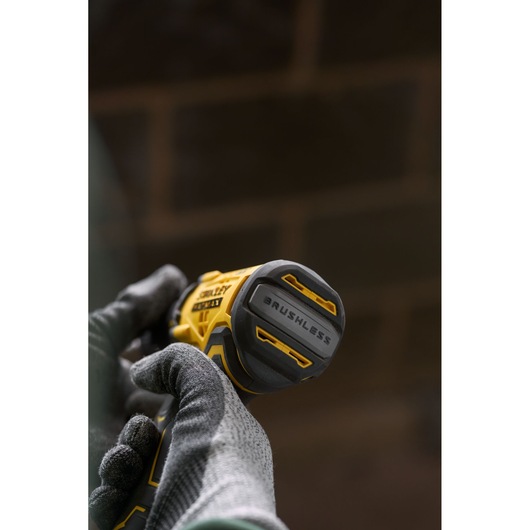 Close-up photo of STANLEY SFMCD715D2K brushless cordless drill held in gloved hands, showing the tool's base.
