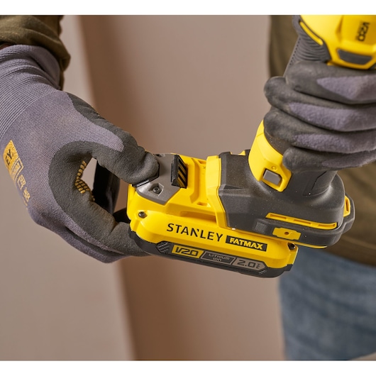 Photo of STANLEY SFMCE200B cordless tool with V20 FATMAX battery held by gloved hands.