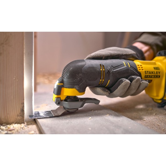 Photo of STANLEY SFMCE500D2K oscillating multi-tool in use, close-up cutting near a baseboard.