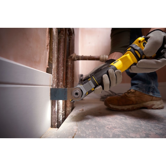 STANLEY SFMCE500D2K multi-tool cutting baseboard in construction setting, close-up action shot.