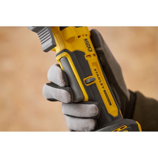 Photo of STANLEY SFMCE510B photography category cordless tool, close-up of handle held by gloved hand.