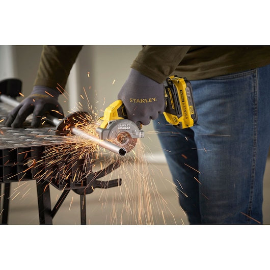 STANLEY SFMCM300D2 cordless mini circular saw cutting metal pipe, sparks flying, worker wearing gloves.
