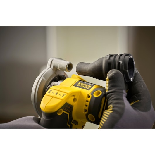 Close-up of STANLEY SFMCM300D2 tool being operated with gloved hands, focusing on attachment process.