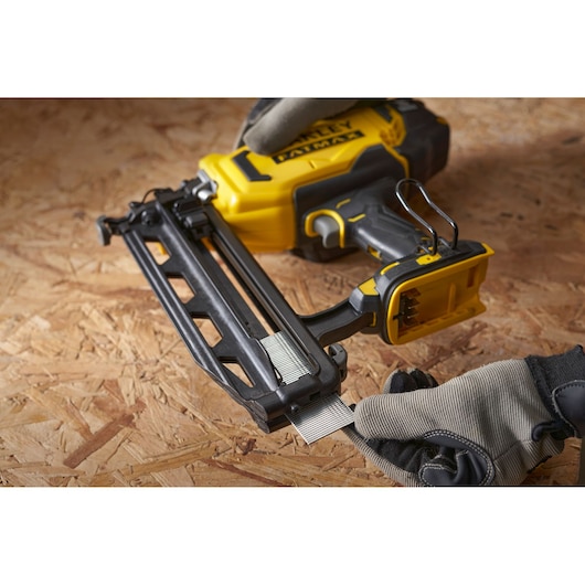 STANLEY SFMCN616B nailer angled view, yellow and black, being loaded with nails on wooden surface.