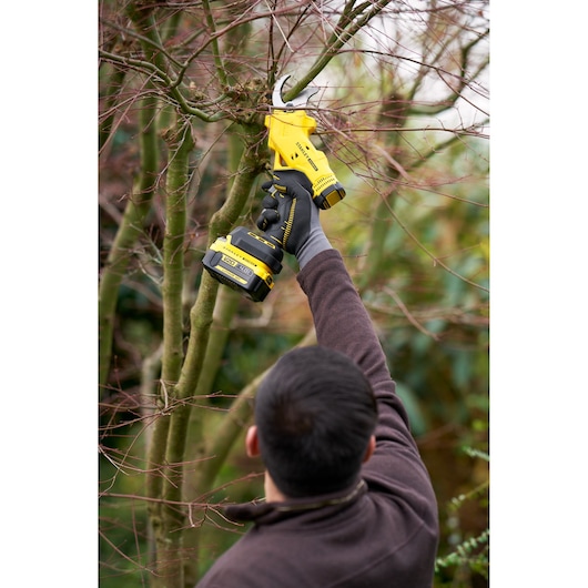Photo of STANLEY SFMCPP32M1 cordless pruning shears cutting tree branches outdoors.