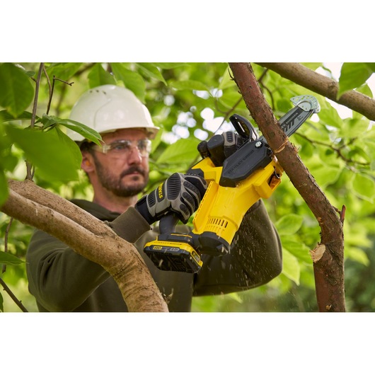STANLEY SFMCPS415D1 cordless pruner cutting tree branch outdoors, close-up in garden setting.