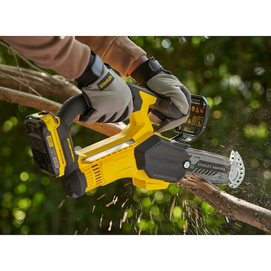 STANLEY SFMCPS415D1 cordless pruning saw cutting tree branch outdoors, close-up action view.