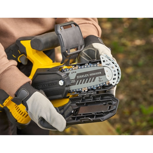STANLEY SFMCPS415D1 FatMax chainsaw close-up, showing chain bar and protective gloves outdoors.
