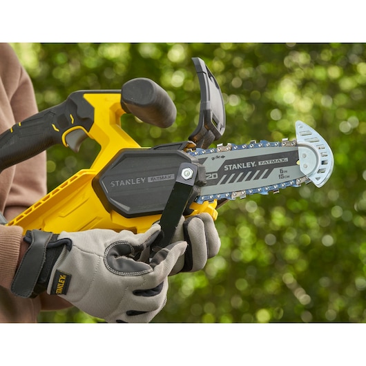 STANLEY SFMCPS415D1 chainsaw close-up in use, yellow and black body, FATMAX branding, outdoor background.