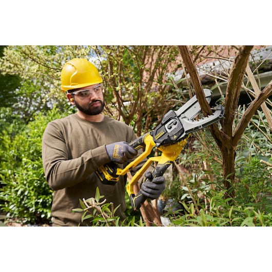 STANLEY SFMCPS515B cordless pruner saw in use, cutting tree branches outdoors.