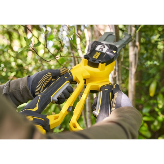 STANLEY SFMCPS515B photography of cordless yellow and black pruning shears in use outdoors.