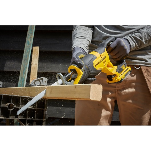 STANLEY SFMCS300D2K reciprocating saw in use cutting wood, close-up side view, yellow and black cordless tool.