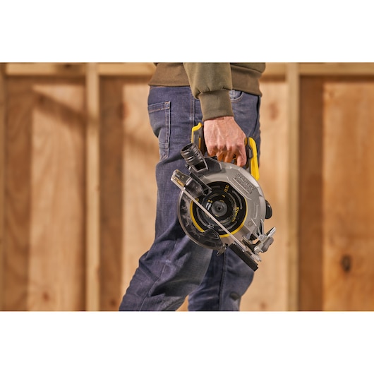 STANLEY SFMCS550M2K circular saw held by person, yellow and black handle, photo in workshop setting.