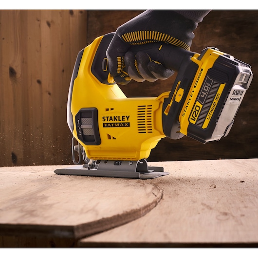 STANLEY SFMCS600B cordless jigsaw in use cutting wood, close-up side angle, yellow and black design.