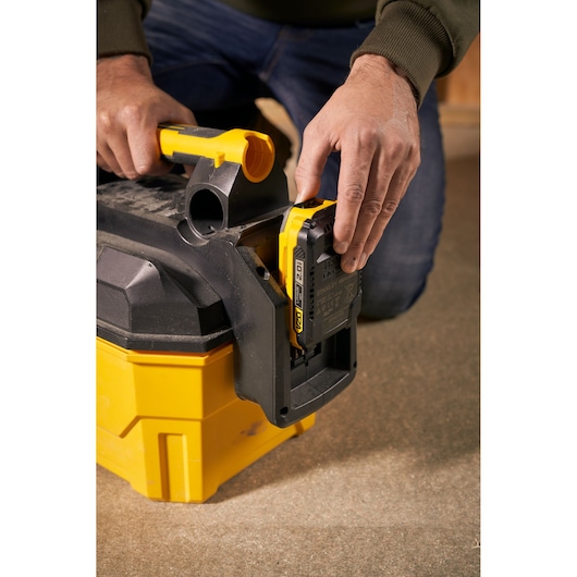 STANLEY SFMCV002B portable vacuum cleaner battery compartment close-up with person inserting battery.