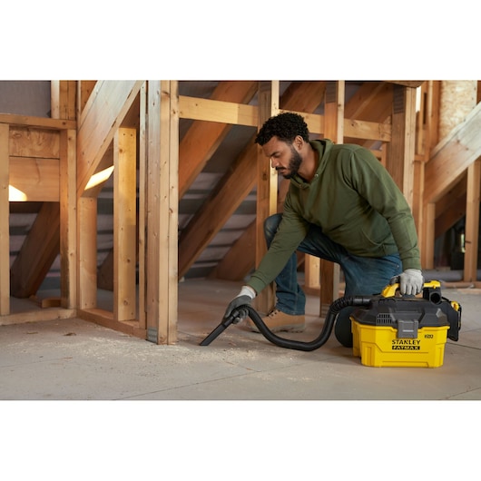 Photo of STANLEY SFMCV002B wet dry vacuum cleaner in use, cleaning construction dust in a wooden attic.