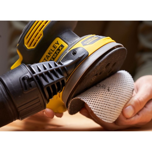 STANLEY SFMCW220B sander held in hand, mesh sanding pad being attached, close-up view.