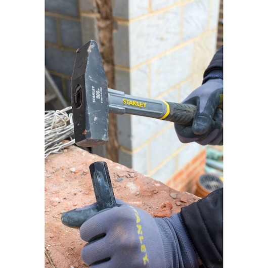 STANLEY STHT0-51909 club hammer with black-yellow handle in use on a brick, construction work context.