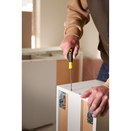 STANLEY STHT0-60335 screwdriver used on white furniture, close-up photo of tool in action.