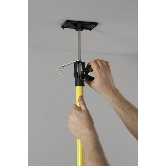 STANLEY STHT1-05932 telescopic drywall support pole shown being adjusted against ceiling.