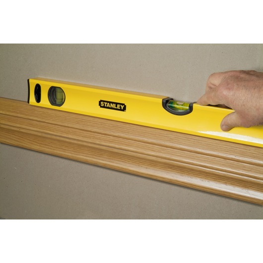 STANLEY STHT1-43103 spirit level checking alignment on wood trim, close-up side angle.