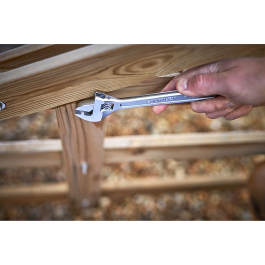 STANLEY STHT13156-0 adjustable wrench used on wooden fence outdoors.