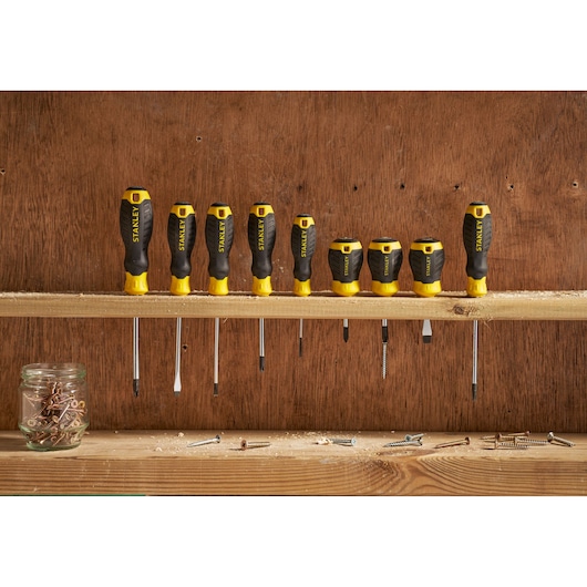 STANLEY STHT16157-0 screwdriver set with black and yellow handles arranged on a wooden shelf.