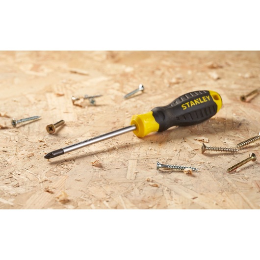 Stanley STHT16163-0 black and yellow Phillips screwdriver on wood with scattered screws.