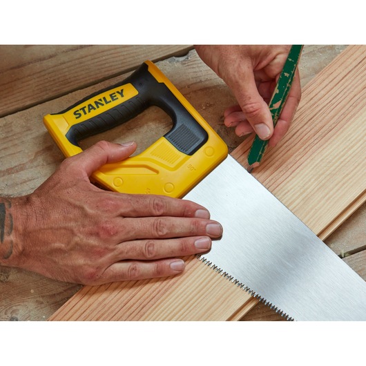 Photo of STANLEY STHT20349-1 hand saw with yellow and black handle on wooden planks, close-up angle.