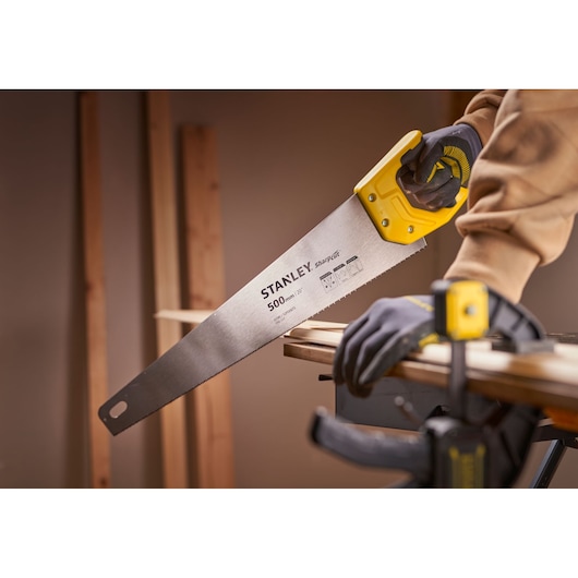Photo of STANLEY STHT20371-1 handsaw with yellow handle cutting wood, close-up side view.