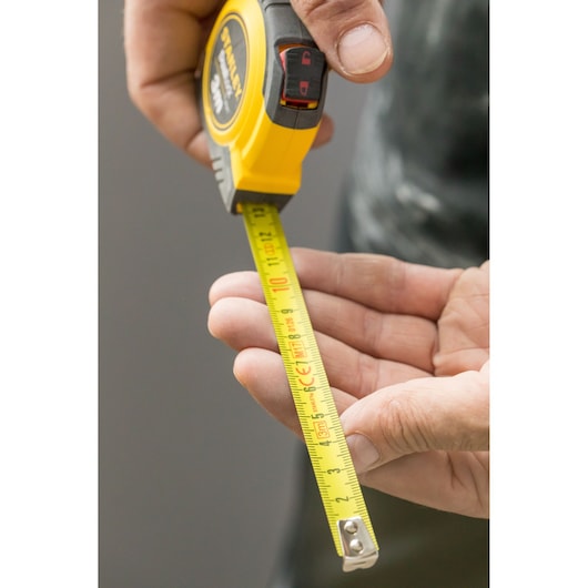 Photo of STANLEY STHT36802-0 tape measure extended, yellow casing, held in hand, close-up view.