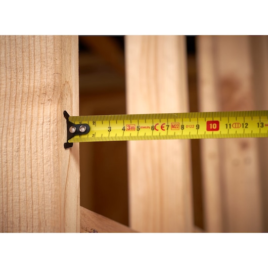 STANLEY STHT37230-0 tape measure extended on wooden surface, close-up side angle.