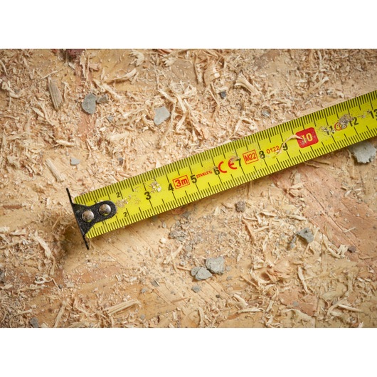 STANLEY STHT37230-0 yellow tape measure close-up on wood with sawdust, photography