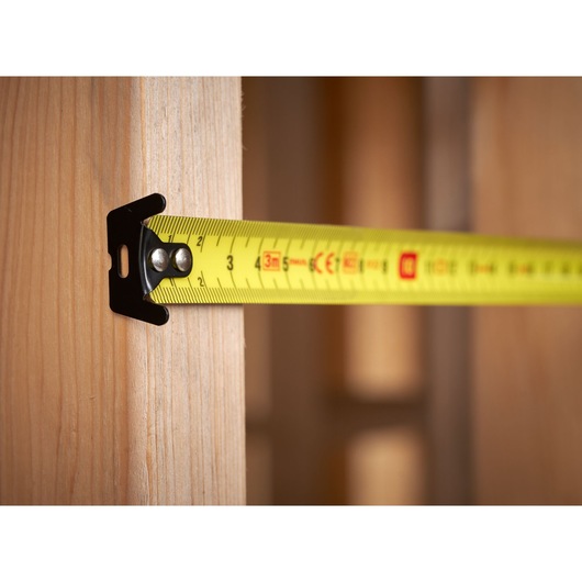 STANLEY STHT37230 tape measure extended across wooden beam, close-up side view, photography.