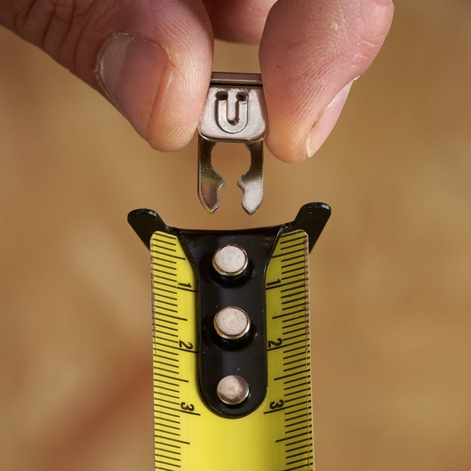 STANLEY STHT37232 tape measure close-up with yellow blade and accessory held by hand.