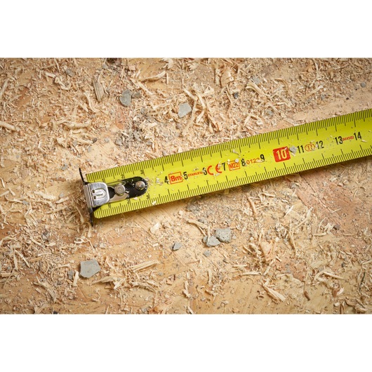 STANLEY STHT37232 tape measure photography showing yellow blade on sawdust surface.