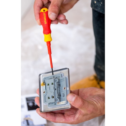 Photo of STANLEY STHT60031-0 insulated screwdriver being used to install an electrical outlet, close-up.